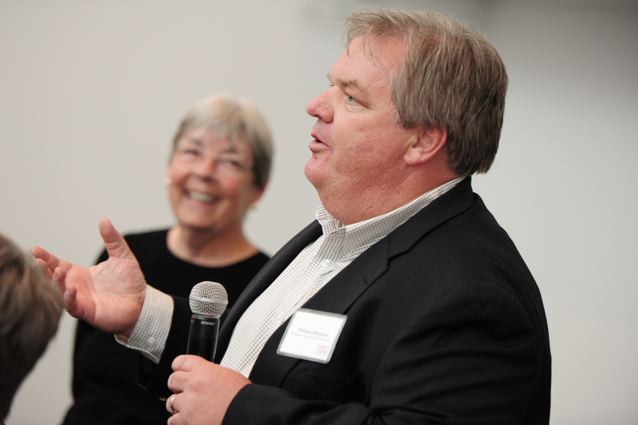 Bill Shannon speaking, with Janice Rohlf pictured in the background