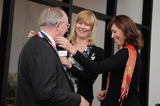 Kathryn Martin and Karen Rohlf presenting F. James Rohlf with a medal