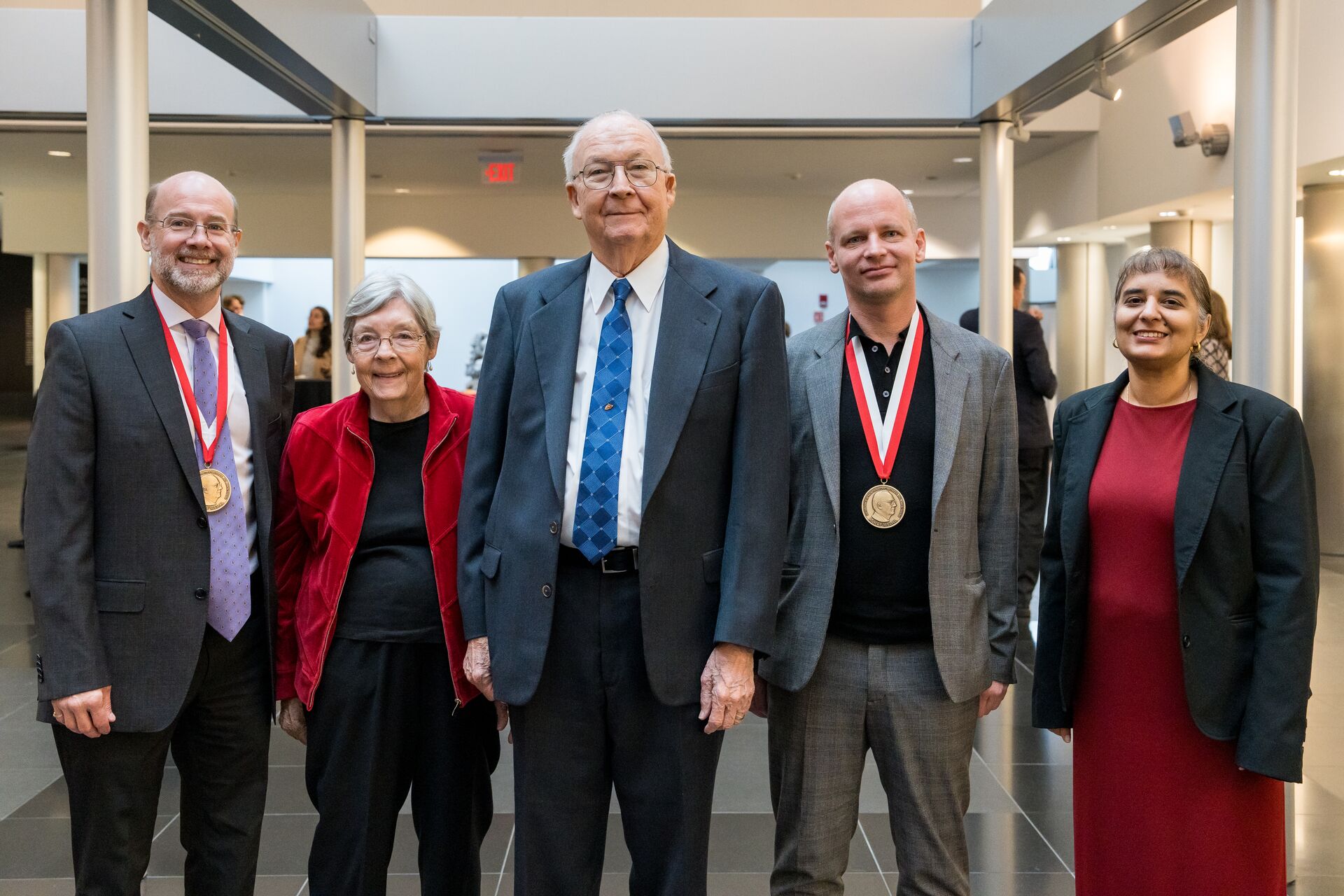 A group photograph of Dean Adams wearing his medal, Janice Rohlf, Jim Rohlf, Philipp Mitteroecker wearing his medal, and Surita Bhatia