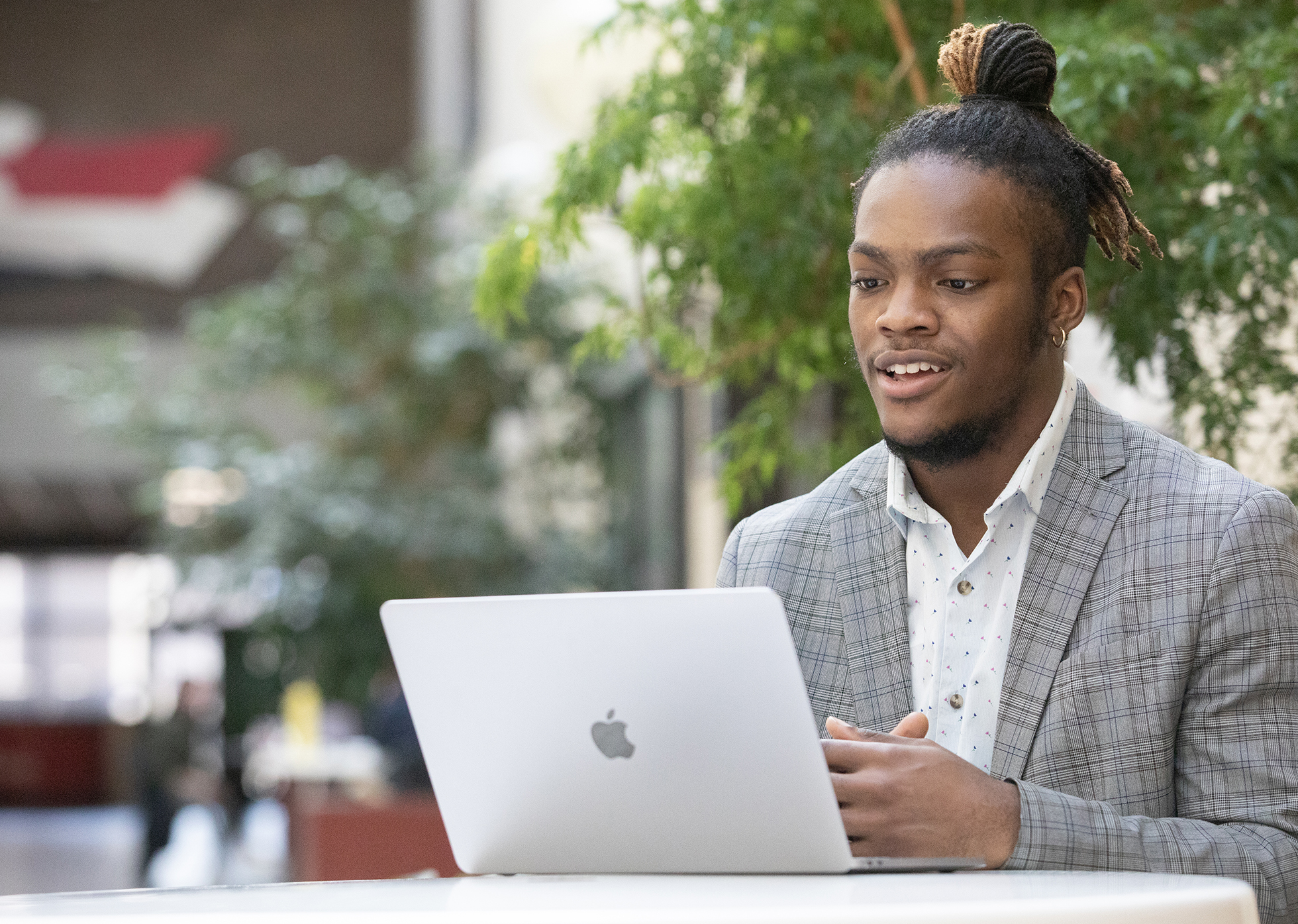 Student in a suit on his laptop outside