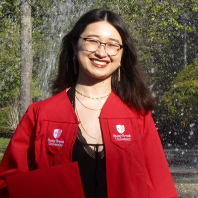 female wearing glasses and red graduation gown, hold graduation cap