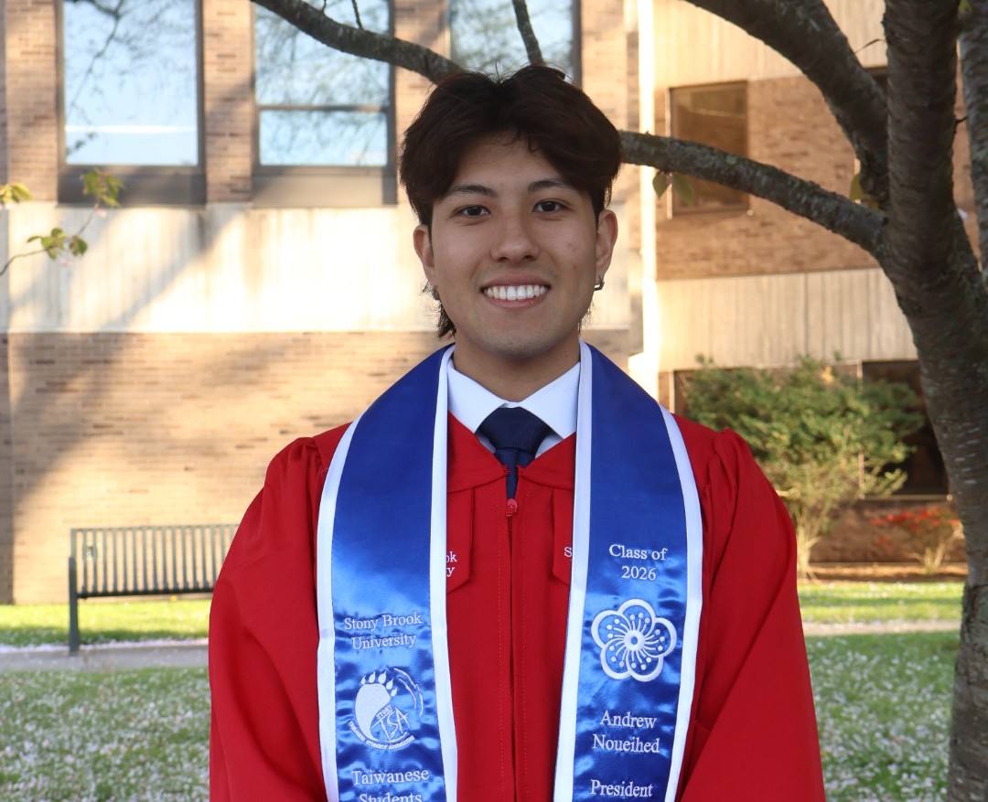 Andrew Noueihed wearing a Stony Brook University red graduation gown