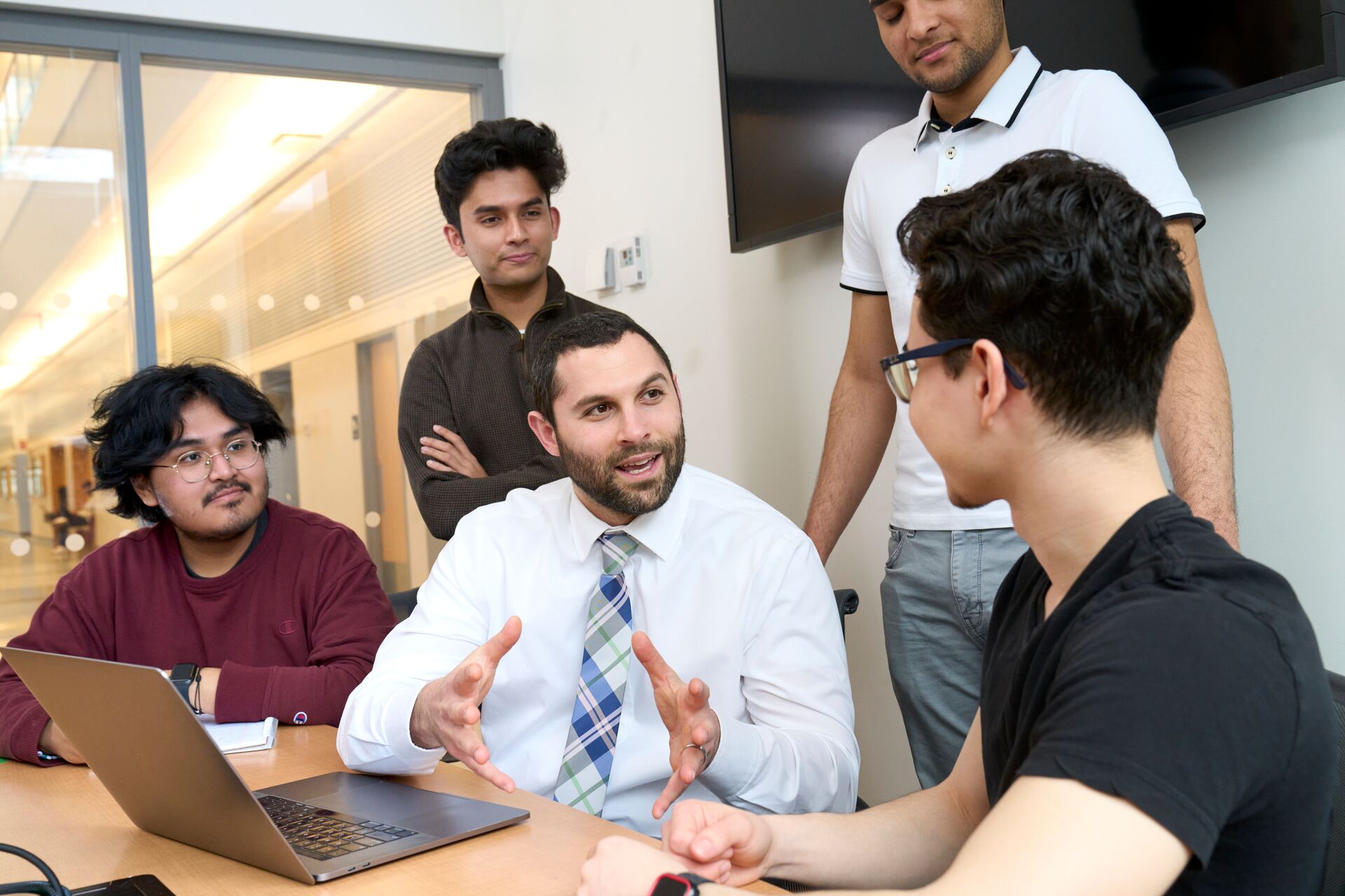 An advisor talking with a group of students at a table.