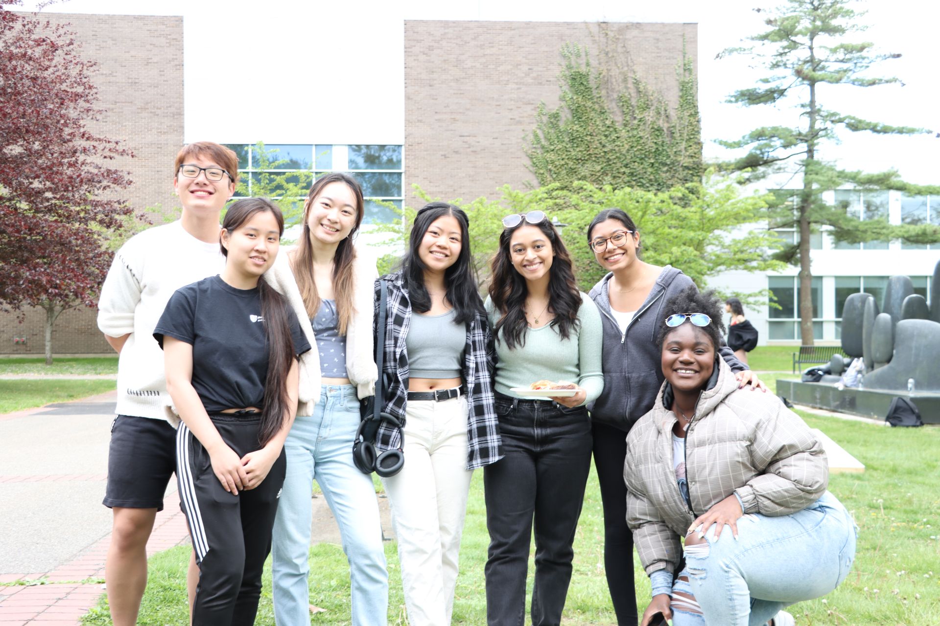 A group of students posing and smiling on the grass.