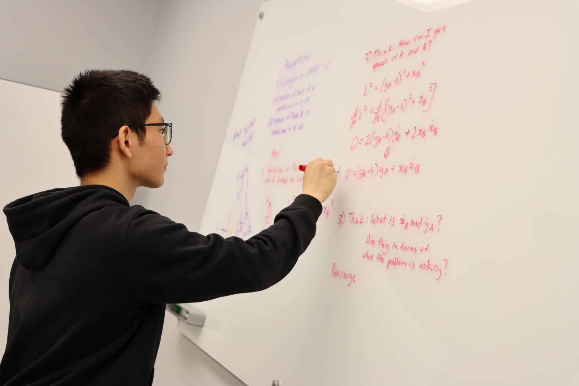 Student writing math equations on a whiteboard.
