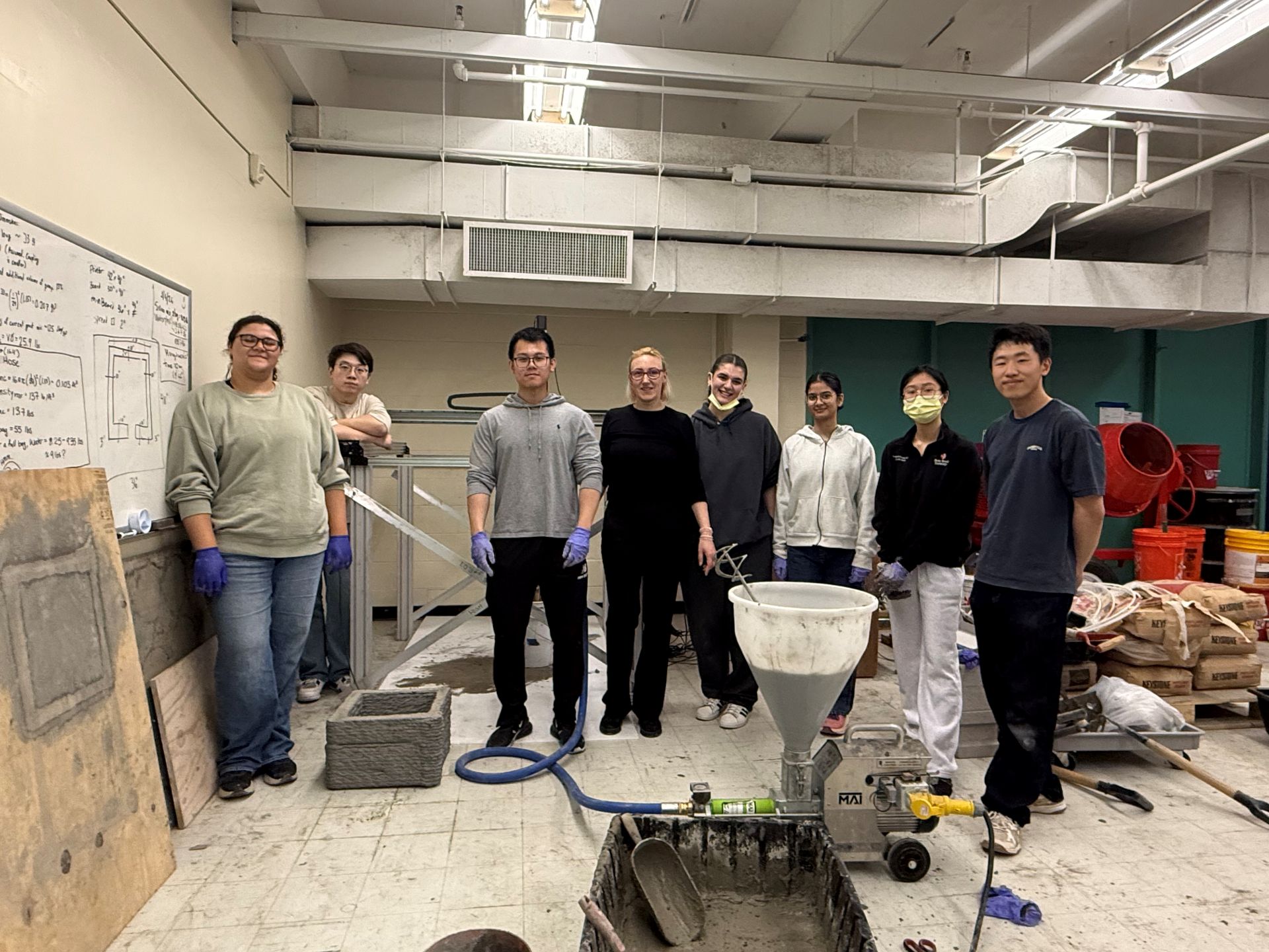 Members of the printing structures team standing in the lab with concrete and mixing equipment around them.