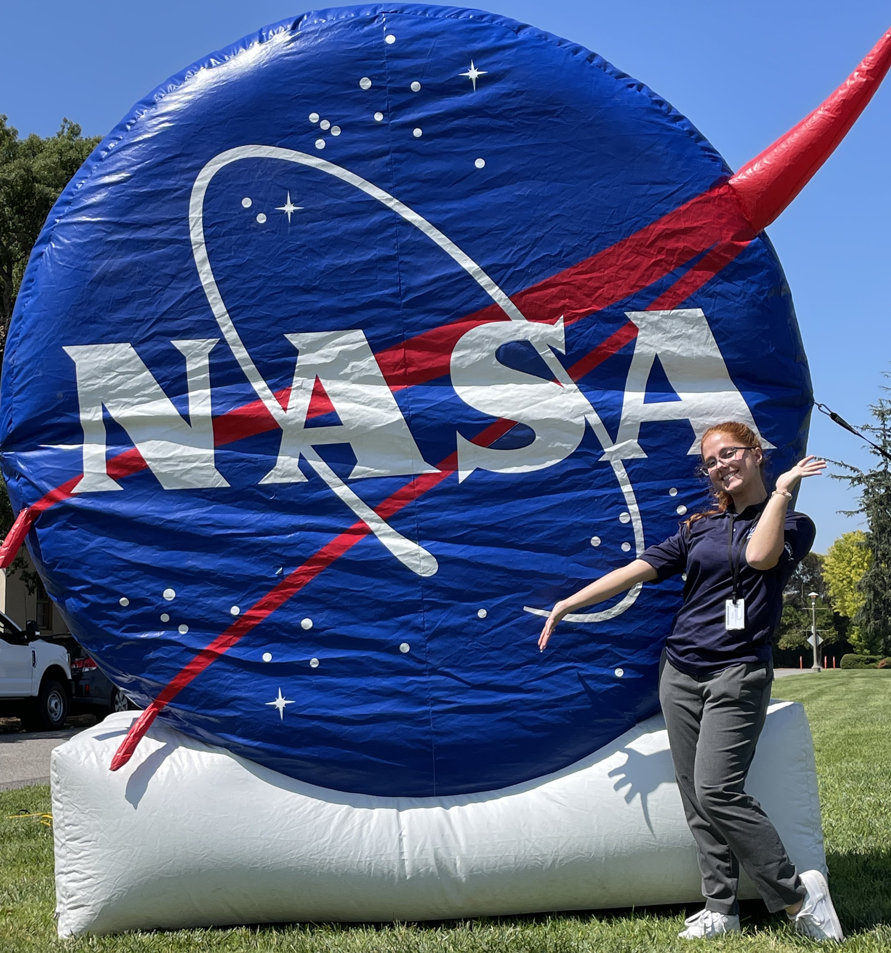 Student posing in front of giant inflatable NASA logo.