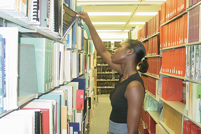 A student looking at books on a library shelf