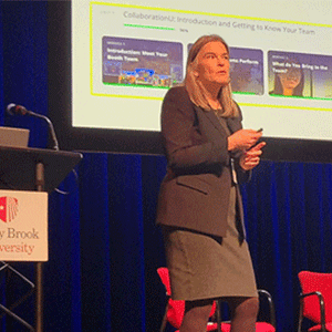 A woman in business attire speaks on stage at Stony Brook University.