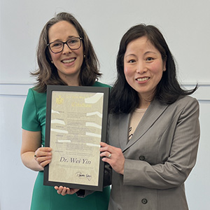 Professor Wei Lin accepts Woman of Distinction certificate from Assemblyman Rebecca Kassay