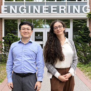 Two professors standing next to each other in front of the Engineering building.