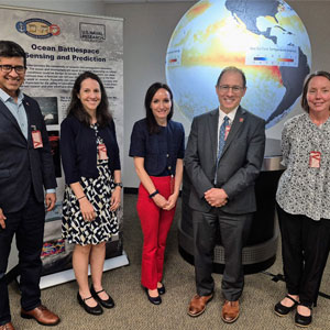 Five people standing in front of a globe posing for photo