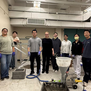 Group of students in a workshop room with cement tools.
