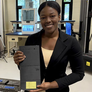 Darla-Ena Boyer holding a model of a “pendulum wall” in lab at Stony Brook University.