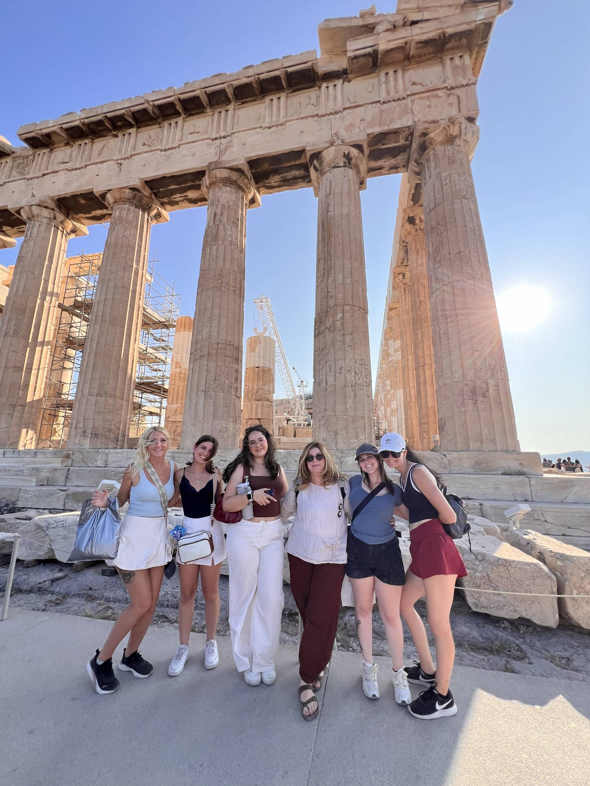 Six students posing for a photo in front of a Grecian ruin
