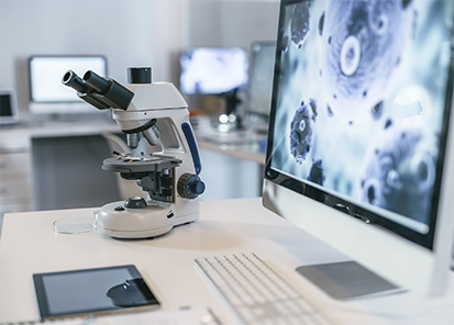 A microscope with a computer screen in the background