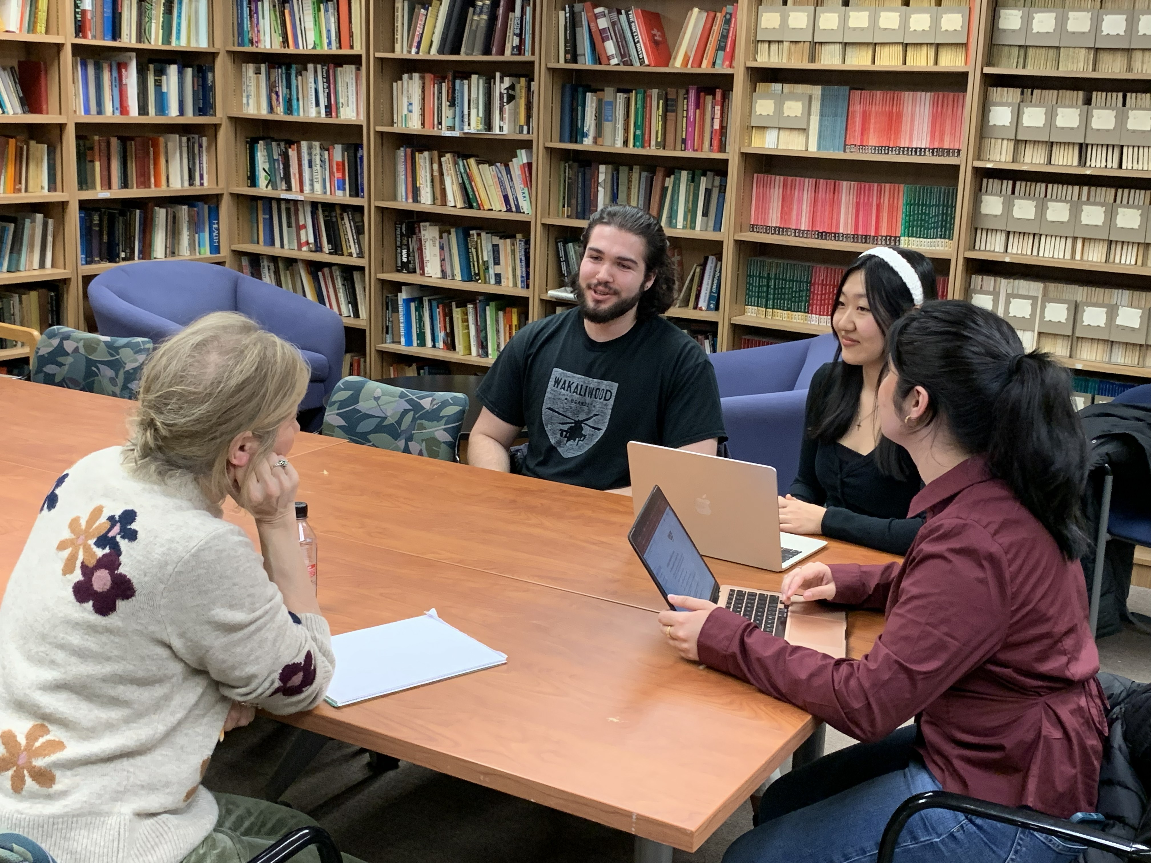 Faculty sitting with students around a table talking in the library