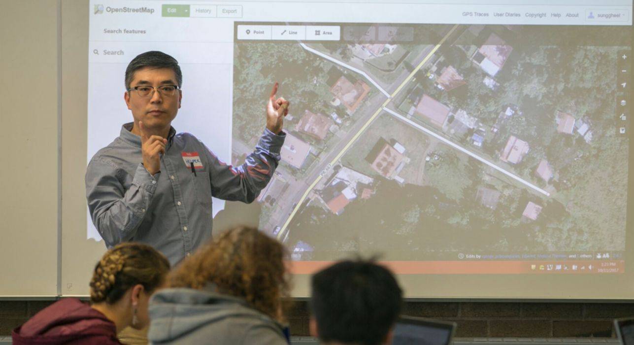 Dr. Gil Jang instructs a GIS class and stands in front of a projector screen