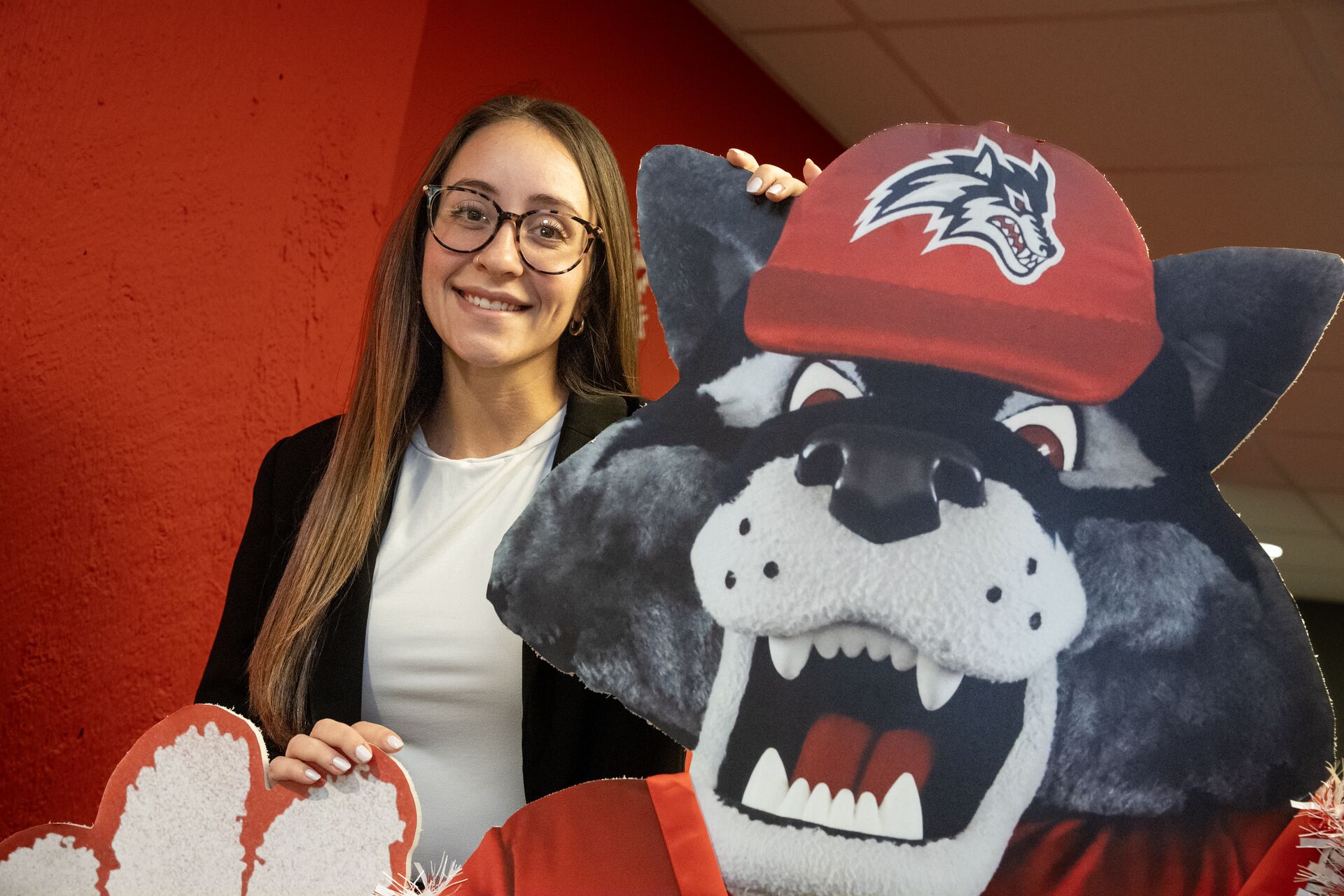 Caucasian woman wearing glasses standing behind poster cutout of Wolfie
