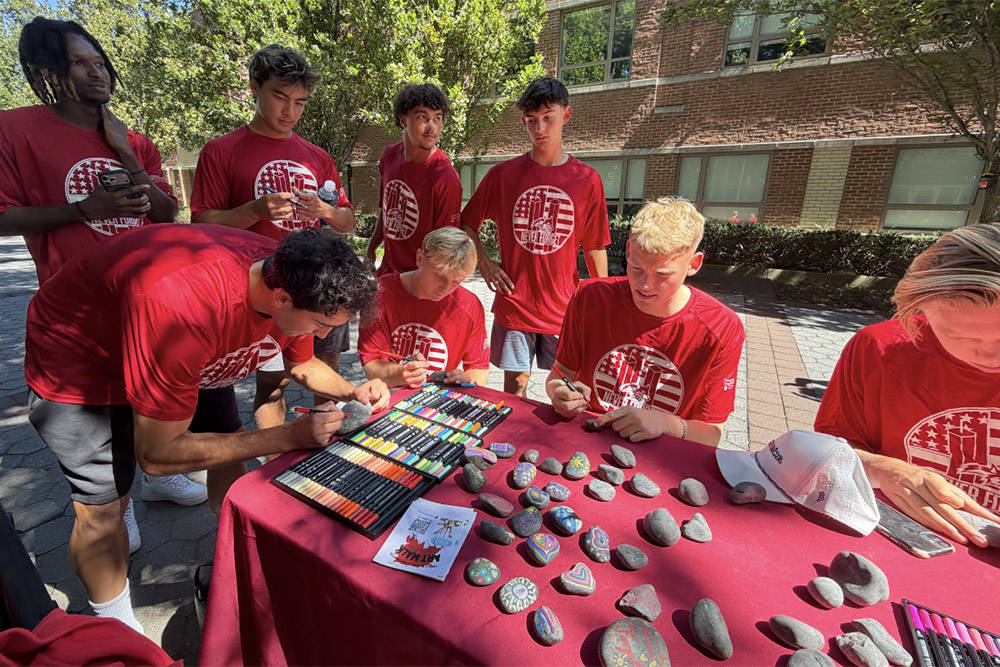 Students painting rocks at table 