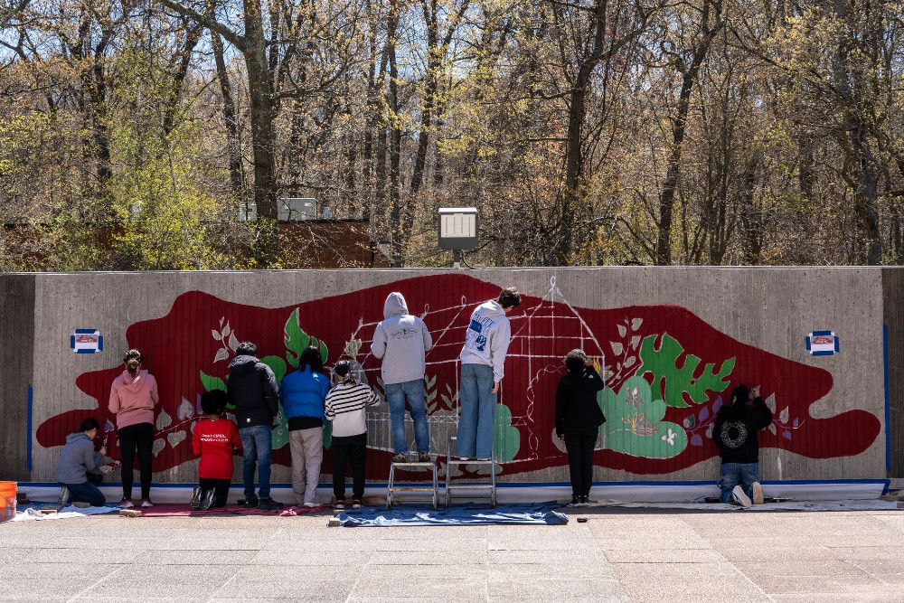 students in front of a wall painting the greenhouse mural 