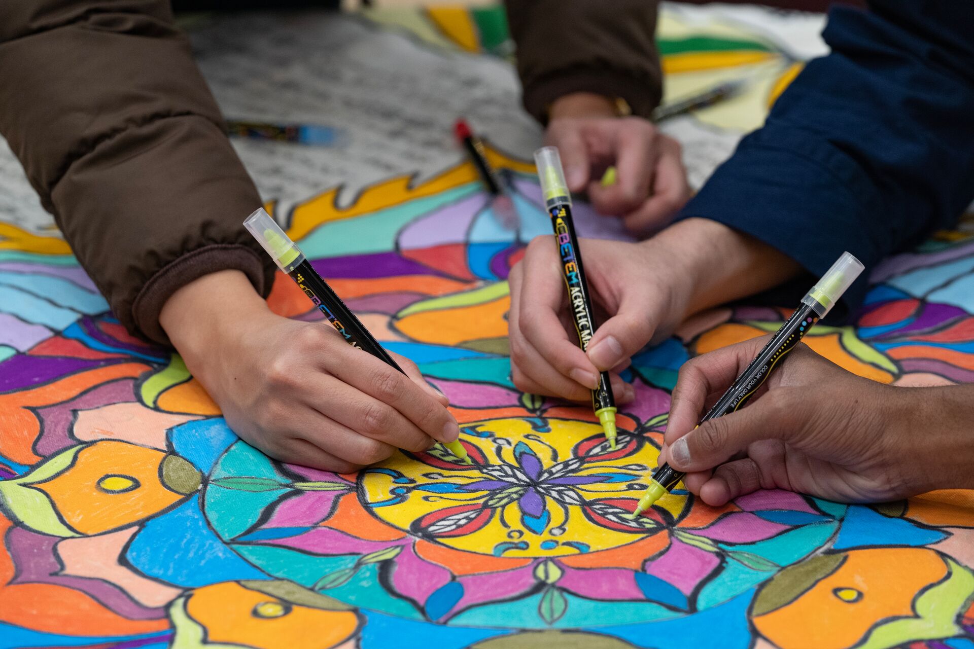three hands coloring in a mandala