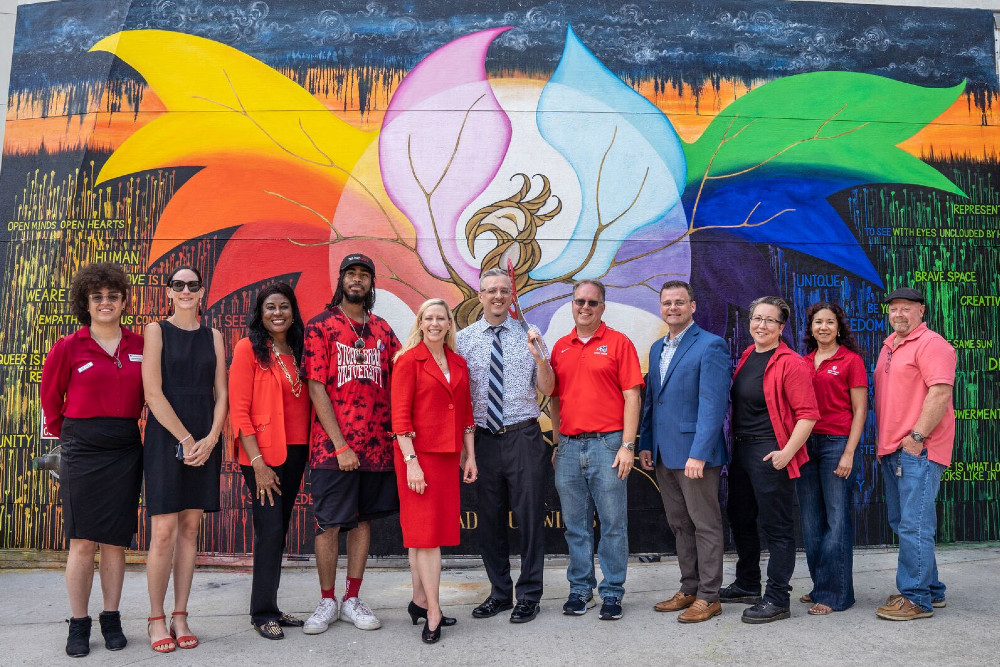 CBC member, SBU students and faculty standing in front of the spread your wings Phoenix mural 