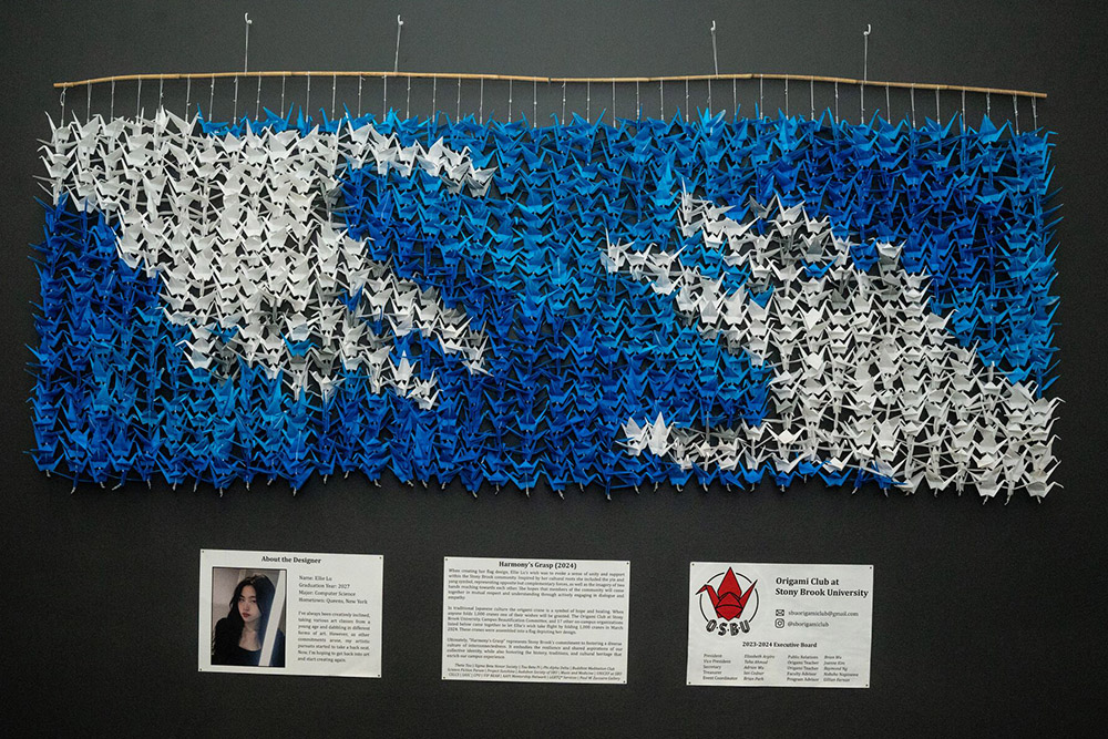 oragami art installation handing from the wall with two hands reaching for each other in it