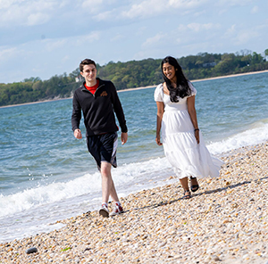 Two Stony Brook students walk along the shore of a beach.