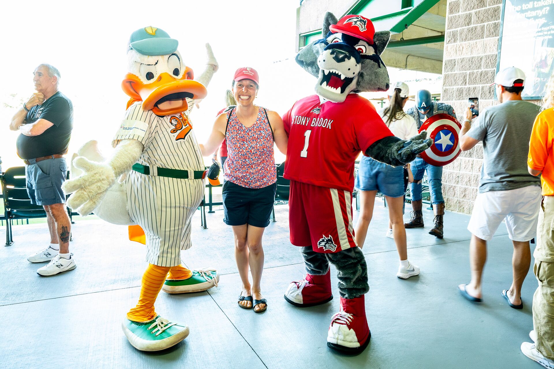 Wolfie and Quacker Jack pose with a Stony brook staff member at a game