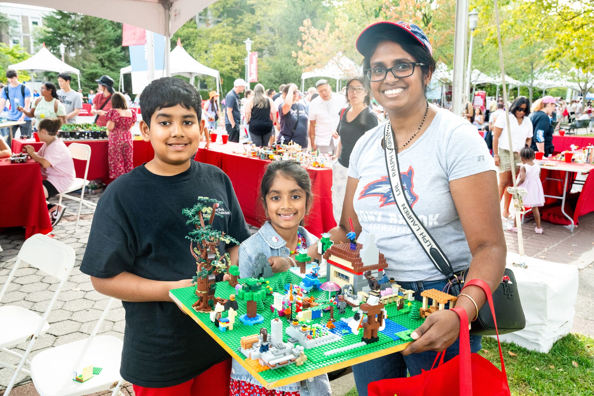 Three people show off their lego creation.