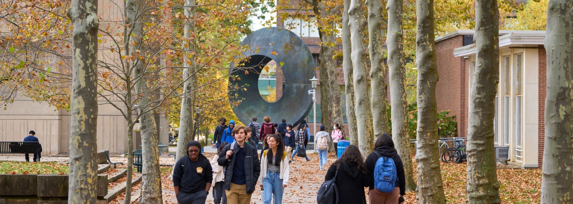 Students on campus mall; statue of umbilic torus in the background