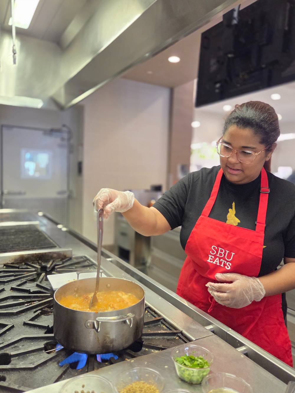 person wearing apron cooking on a stove