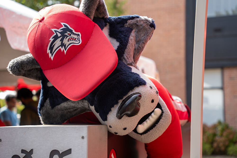 Wolfie layout down on a sign outside during Be Well Fest.