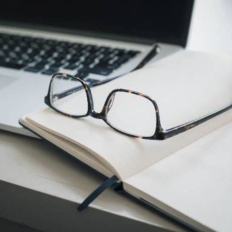 Laptop, notebook, and glasses on a table