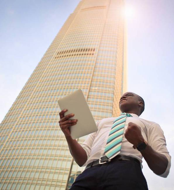 Man in professional clothes standing in front of a skyscraper