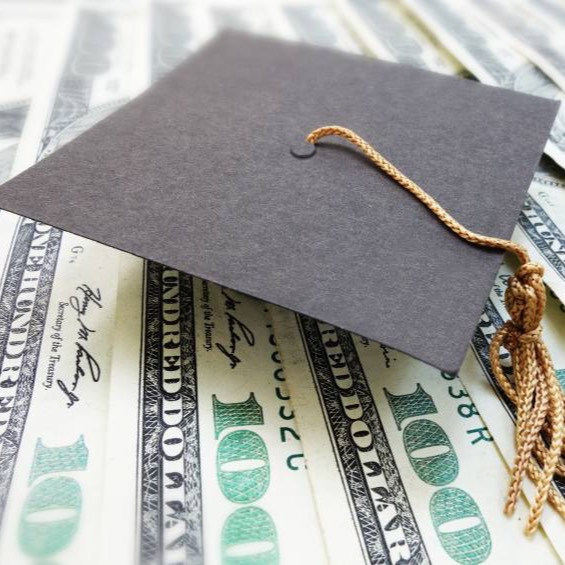 Graduate cap sitting on one hundred dollar bills