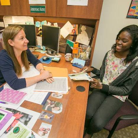 Advisor sitting at a desk speaking with a student