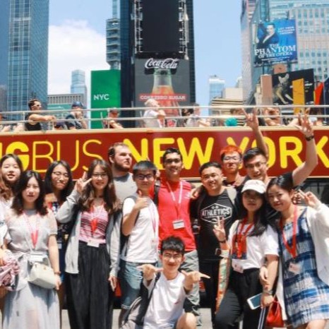 Students in NYC standing in front of a tourist bus