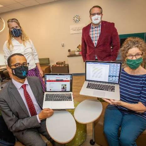 Faculty posing with laptops depicting an online workshop