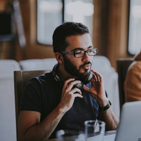 Employee holding headphones looking at a computer