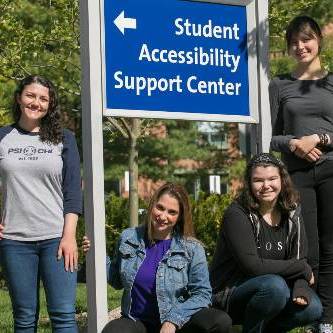 Four people standing next to the SASC sign