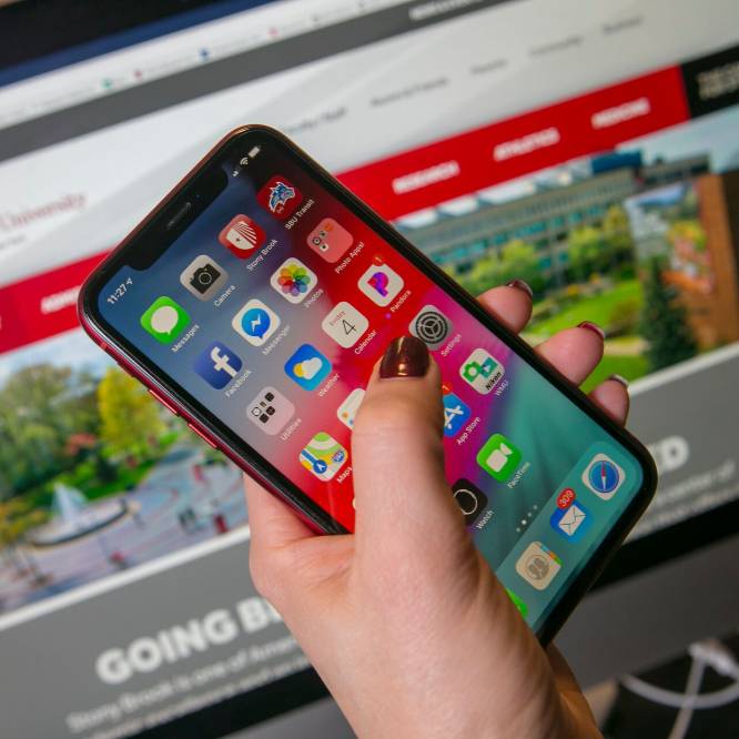 Hand holding phone with Stony Brook apps