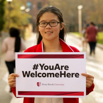 Student holding a You Are Welcome Here sign