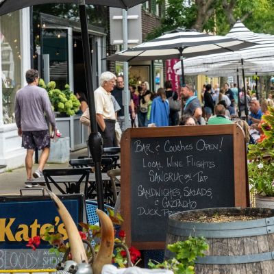 People walking and dining along a busy street in Southampton village