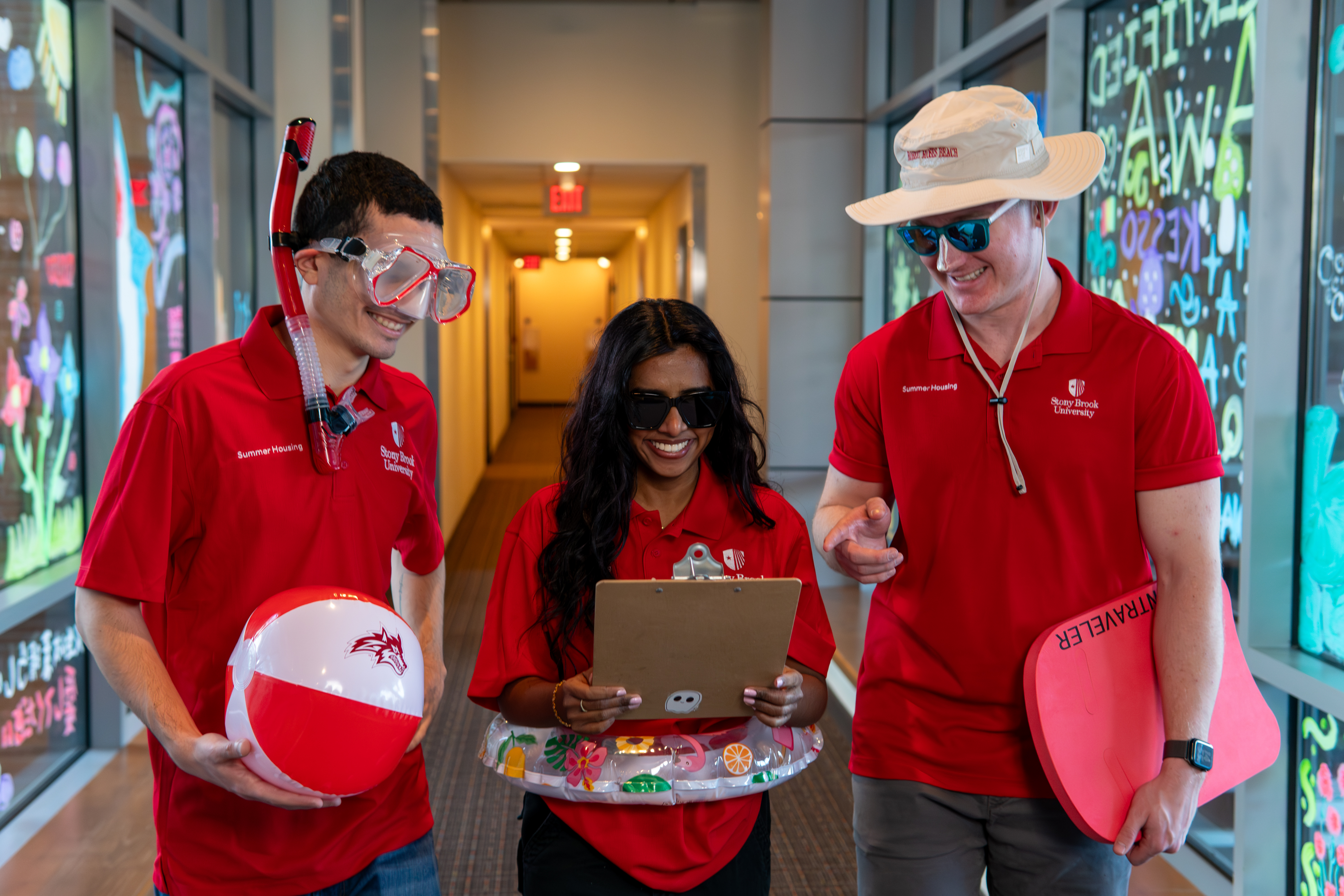 Three summer student staff members pose while wearing summer props