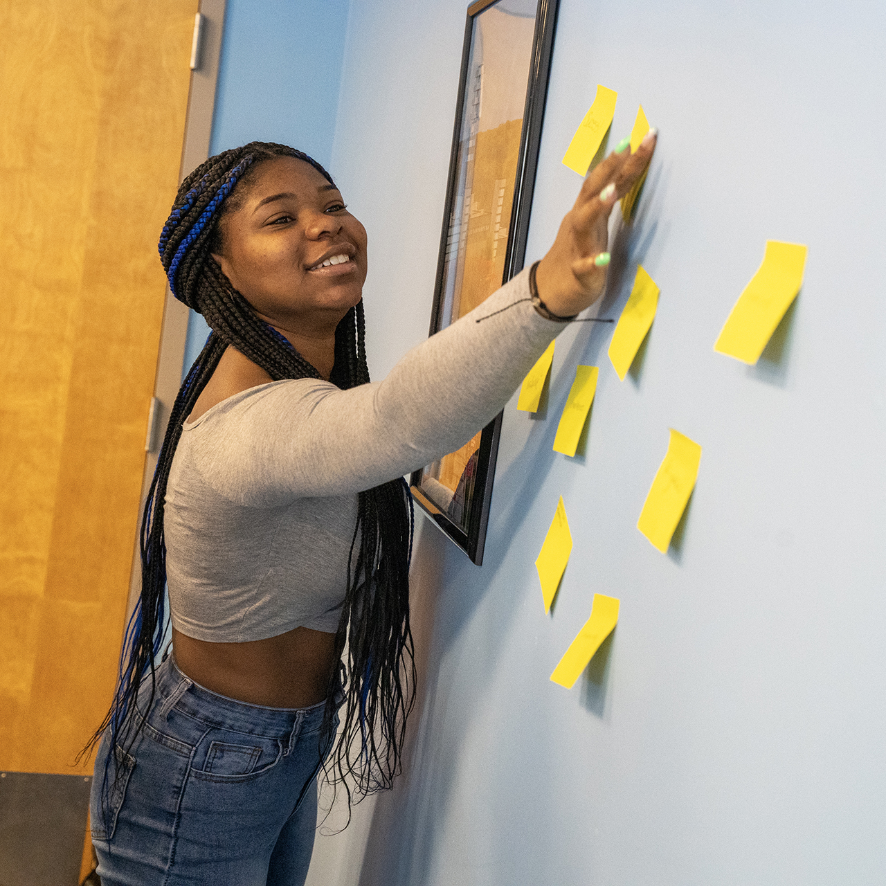 A student placing post-it notes on a board.