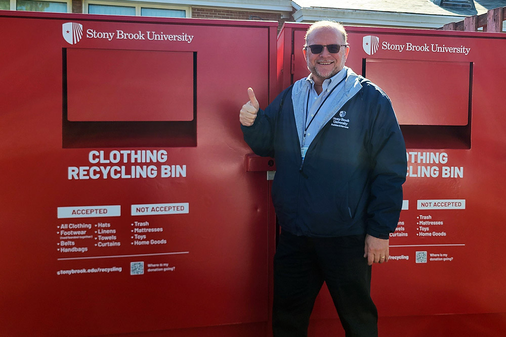 Facilities and Services Manager Michael Youdelman in front of the Red Hot clothing recycling bins.