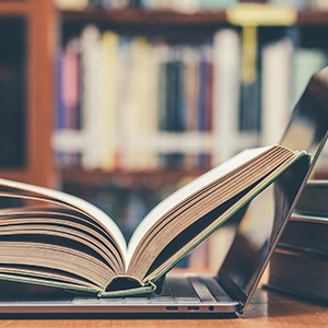 Laptop on a table with an open book