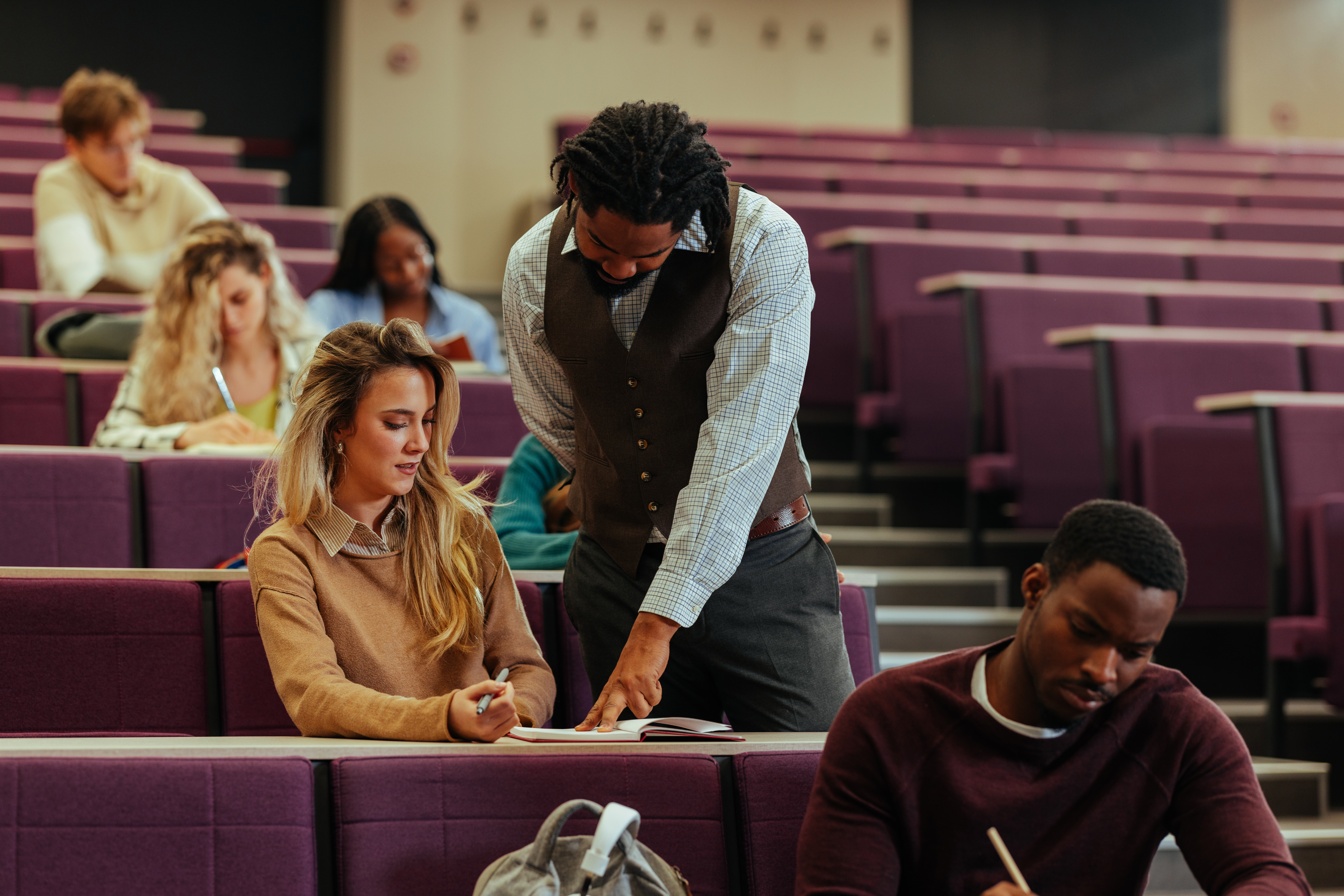 A professor helping a student in a lecture amphitheater 